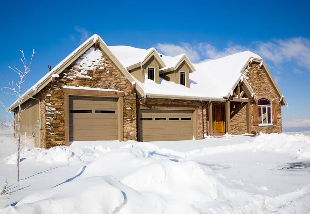 A snow covered luxury home under a clear blue sky.