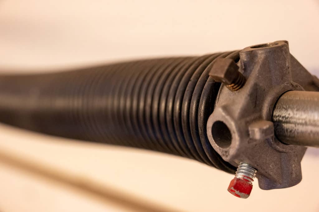 Close up side view of garage door coiled spring; Length-wise perspective of a garage spring
