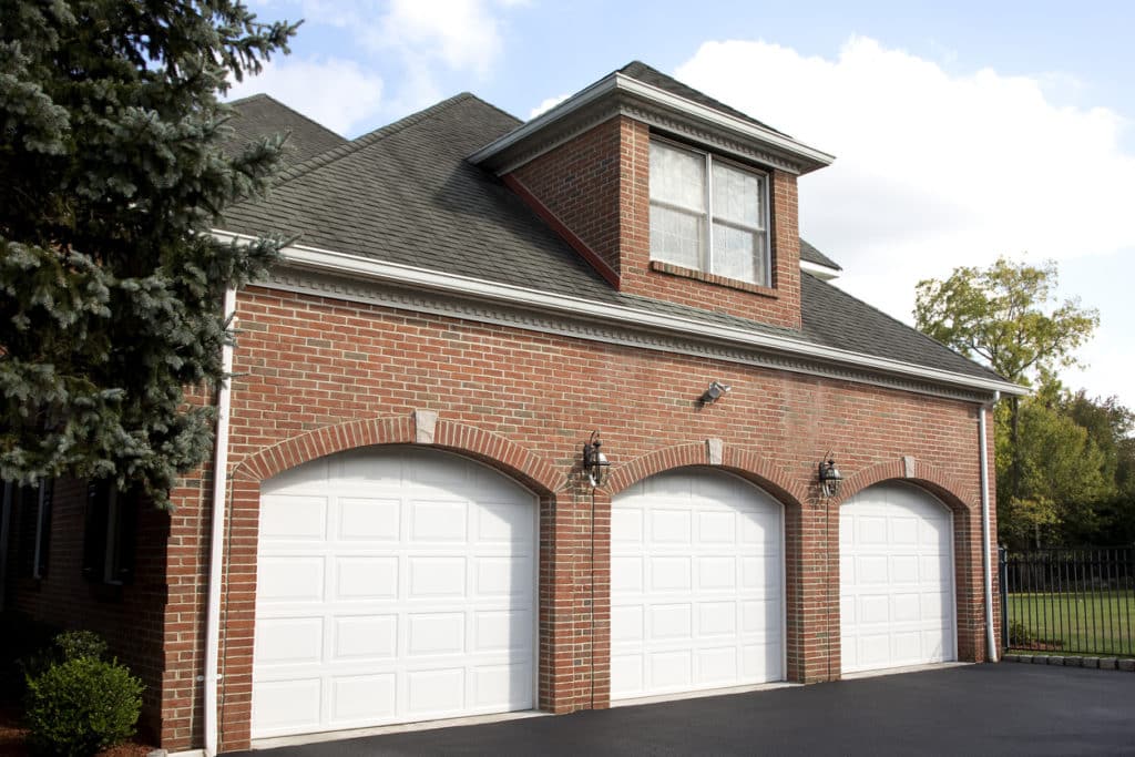 Large house three car garage. A snow covered luxury home under a clear blue sky.