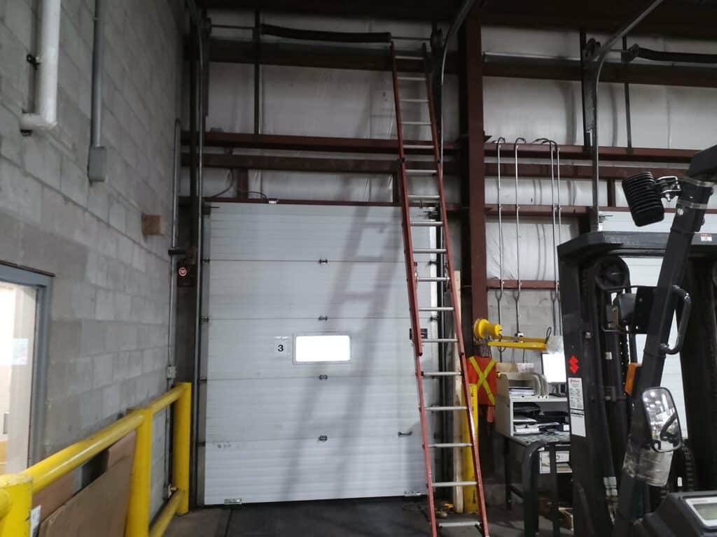 Technician repairing a commercial overhead door in Barrie