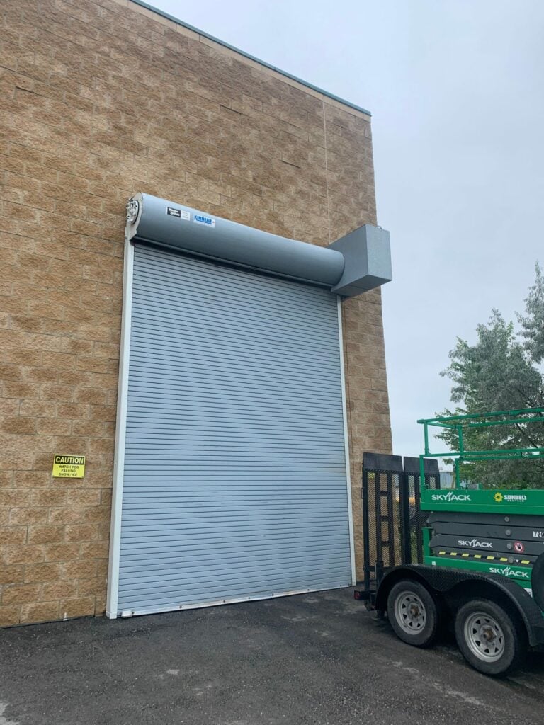 Grey rolling steel door installed on a brick building