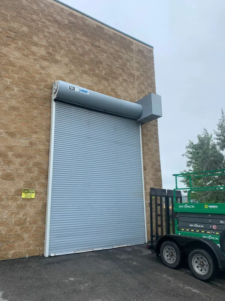 Grey rolling steel door installed on a brick building