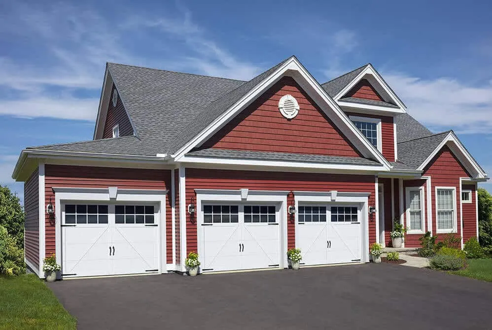 3 white carriage house style garage doors on a home with red siding