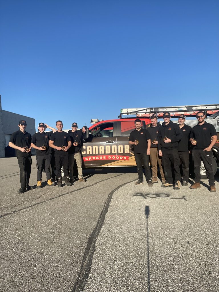 Canadoor Garage Doors team standing beside a branded service truck