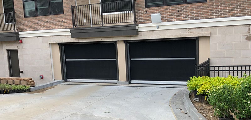 Two black garage doors on the exterior of a condo parking garage