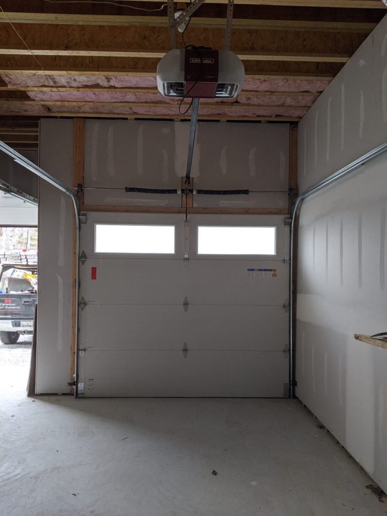 White sectional garage door with a ceiling-mounted garage door opener