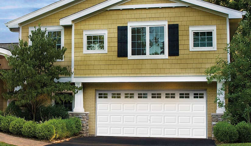 White raised-panel garage door with decorative windows on a residential home
