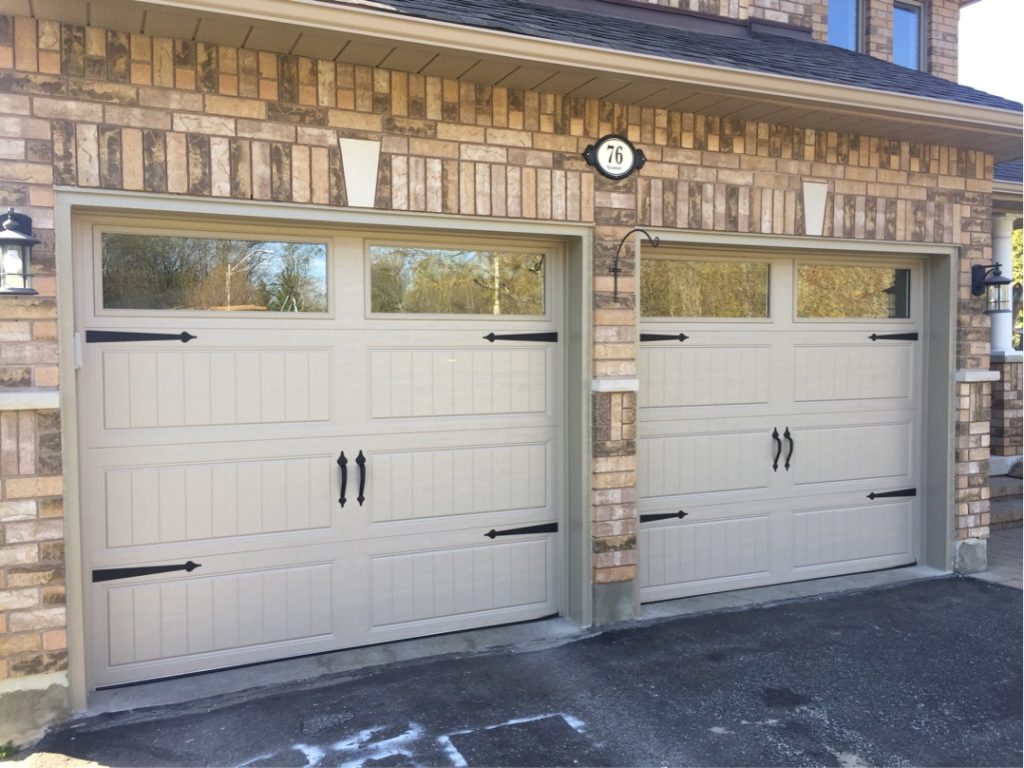 White carriage-style garage doors with decorative hardware and windows