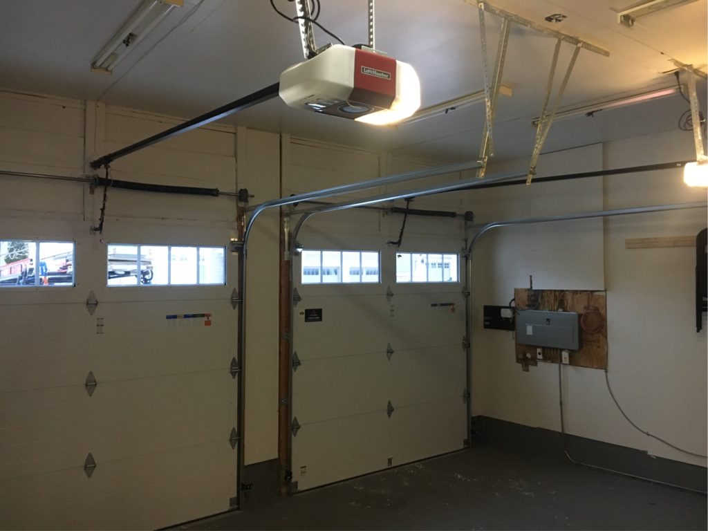 Two white sectional garage doors with overhead door openers